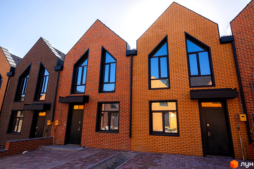 Зовнішній вигляд таунхаусів FORT HOMES з червоної цегли з великими вікнами. Вигляд на прибудинкову територію.