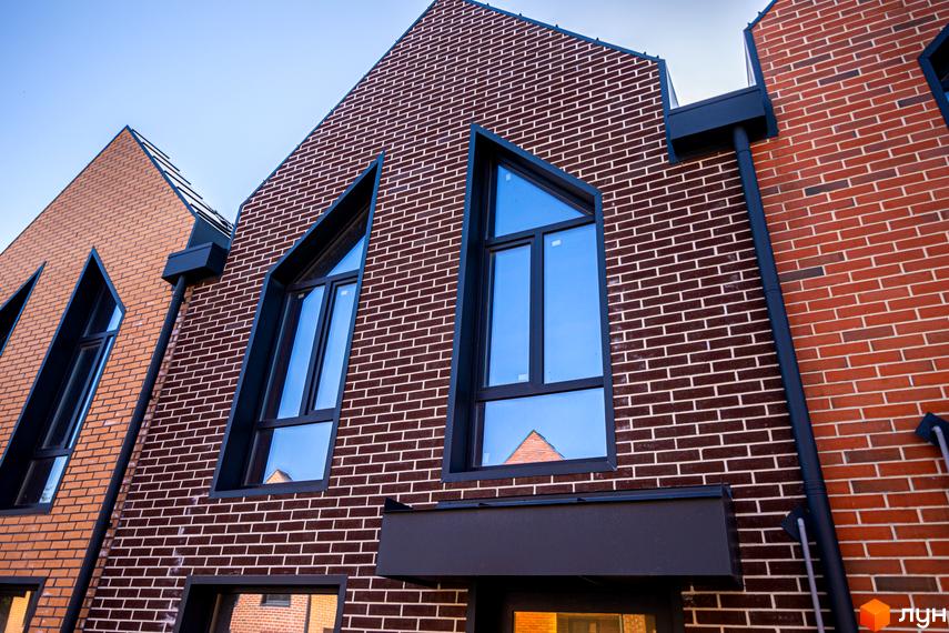 Таунхауси FORT HOMES з цегляним фасадом та незвичайною формою вікон. Зовнішній вигляд будинку з червоної та коричневої цегли підкреслює сучасну архітектуру.