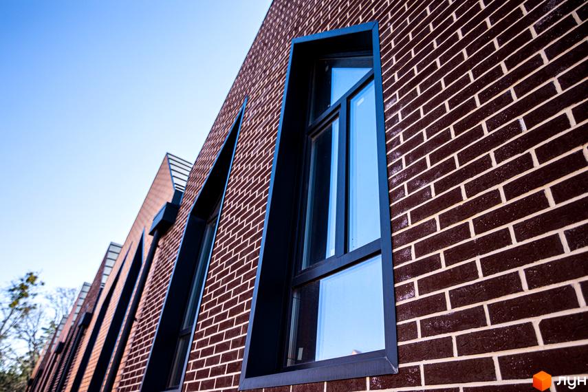 Будинок з коричневої цегли з великими вікнами та гострокутними елементами фасаду. Таунхауси FORT HOMES.