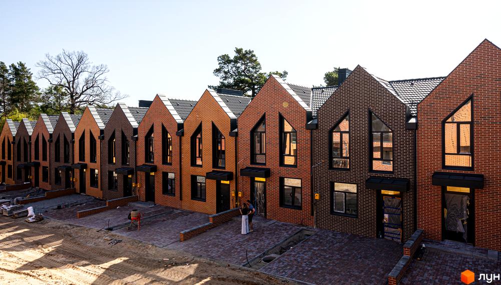 Зображення таунхаусів FORT HOMES з червоної цегли з чорними вікнами. Перед будинками викладена бруківка.