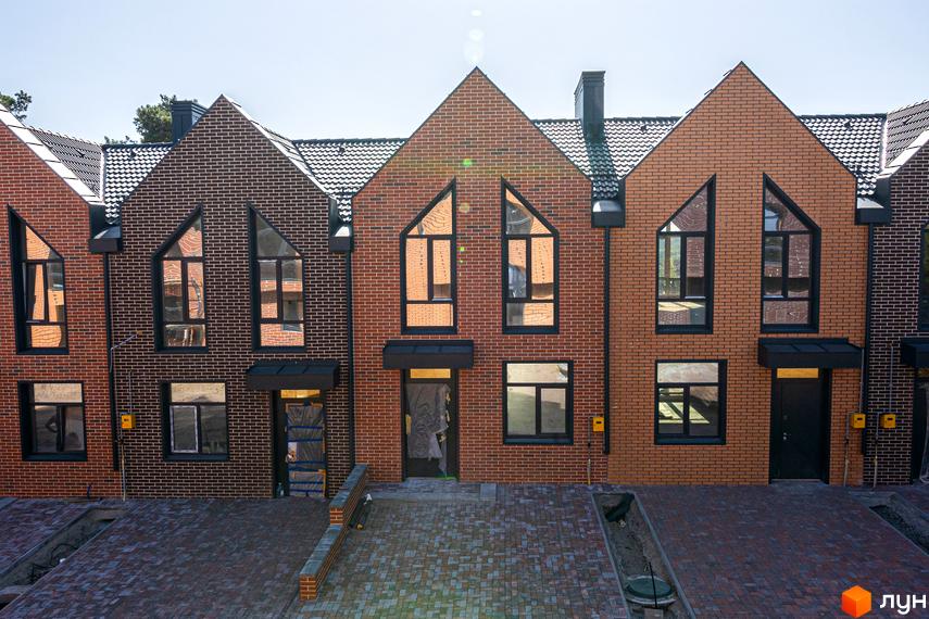 Таунхауси FORT HOMES з цегляним фасадом та великими вікнами. Прибудинкова територія вимощена бруківкою.