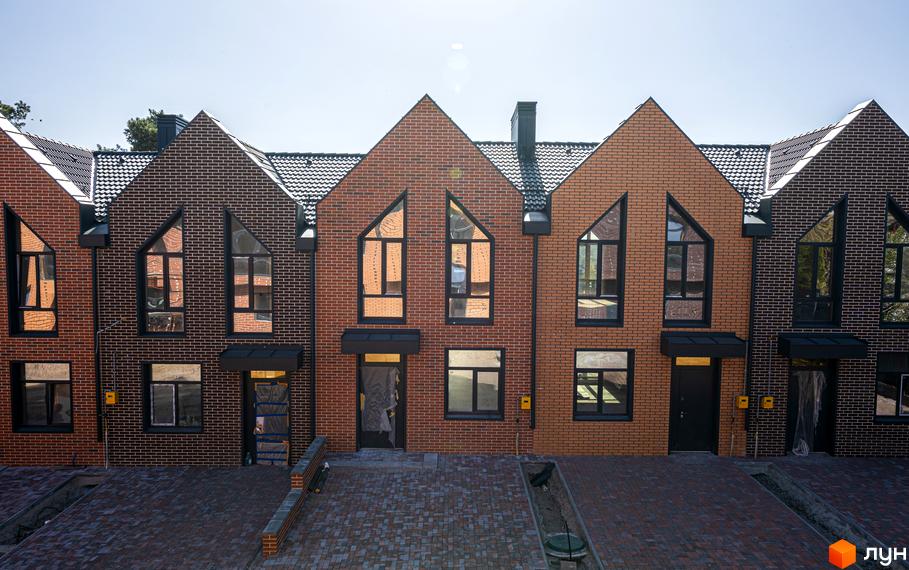 Фасад таунхаусів FORT HOMES з цегли з великими вікнами. Вигляд на прибудинкову територію Житлового комплексу.