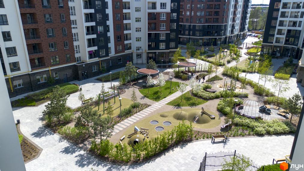 Зовнішній вигляд будинків ЖК Синергія Сіті та їх облаштована прибудинкова територія з дитячими майданчиками та зонами відпочинку.