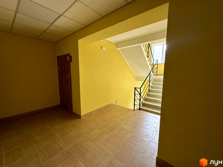 Вхідна група житлового комплексу SMART IDEA з дверима та сходами, що ведуть на верхні поверхи. Стіни пофарбовані в жовтий колір, підлога викладена плиткою.