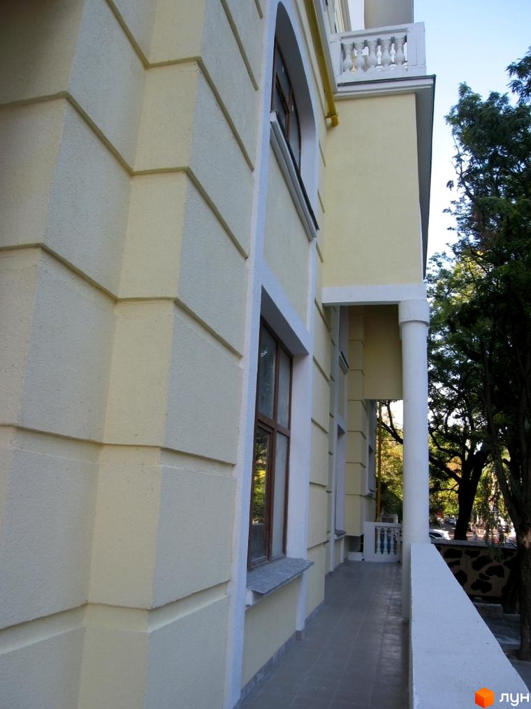 Вигляд фасаду житлового комплексу ЖК Ренесанс з балконом та колонами. Прибудинкова територія з зеленими насадженнями.