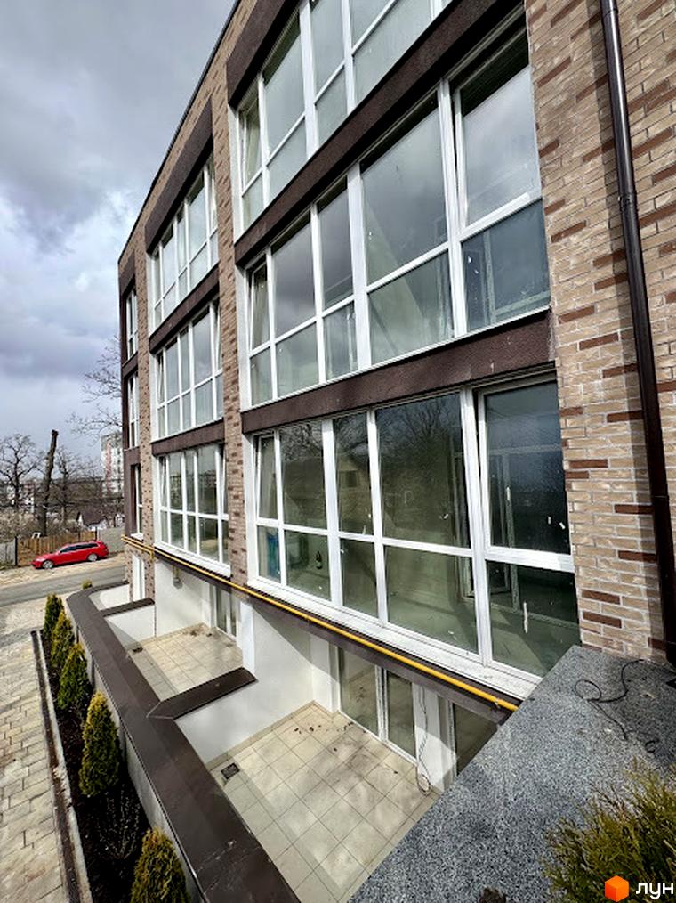 Зовнішній вигляд будинку в Light Residence. Вигляд на фасад з великими вікнами та балконами, а також прибудинкову територію.