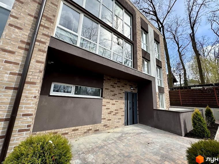 Зовнішній вигляд Клубного будинку Light Residence з великими вікнами та оздобленим фасадом. На передньому плані – вимощена бруківкою територія.