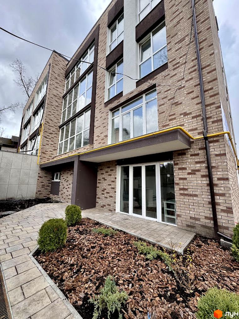 Зовнішній вигляд Клубного будинку Light Residence з оздобленням з цегли. Навколо будинку висаджені декоративні рослини.