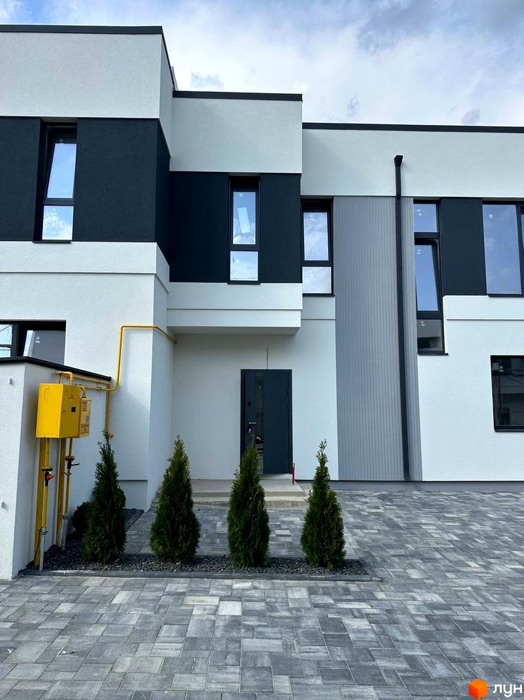 Фасад будинку КМ Jaguar виконаний у білих та темно-сірих тонах з великими вікнами. Перед будинком викладена бруківка та висаджені чотири туї.