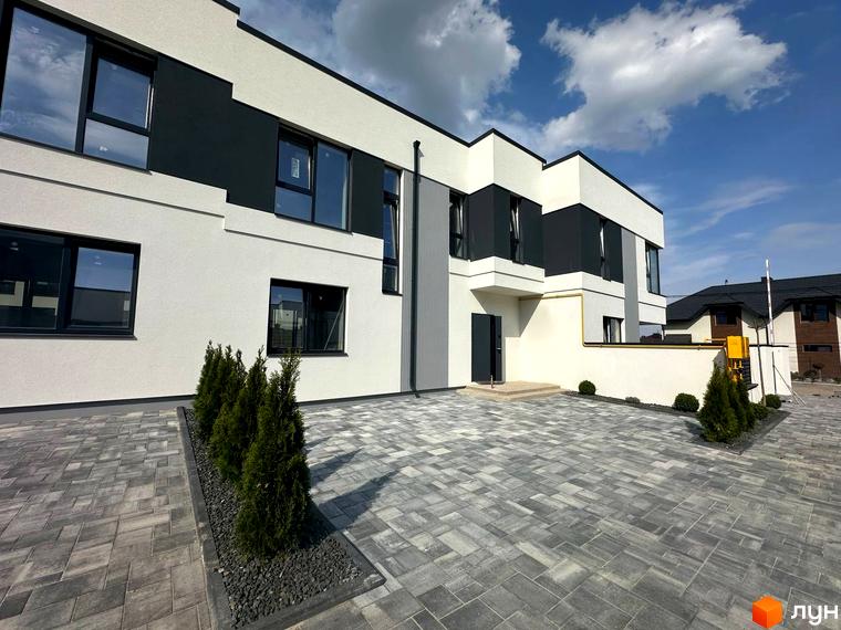 Зовнішній вигляд будинку в Котеджному містечку Jaguar. Перед будинком вимощена бруківка та висаджені декоративні туї.