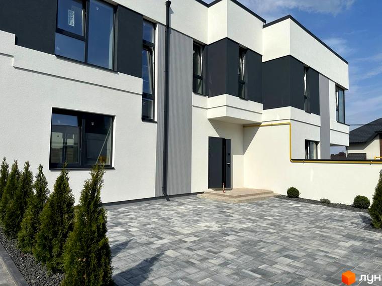 Фасад будинку Котеджного містечка Jaguar з білими та темно-сірими елементами та великими вікнами. Перед будинком бруківка та зелені насадження.