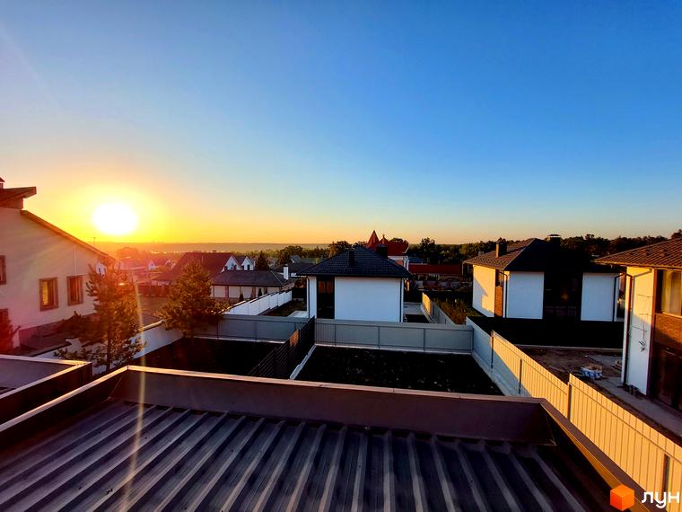 Дуплекси Woodland Hill на заході сонця з білими фасадами та темними дахами. Видно прибудинкові ділянки з огорожами та зеленню.