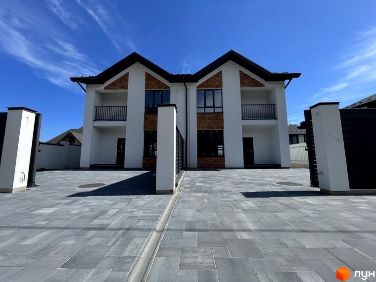 Дуплекси Woodland Hill: два двоповерхові будинки з білими фасадами, темними дахами та цегляними вставками. Прибудинкова територія викладена сірою бруківкою.