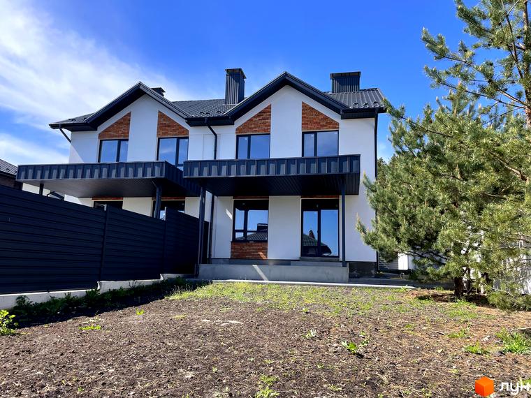 Дуплекси Woodland Hill: Білі дуплекси з чорними дахами та вікнами, цегляними вставками та навісами. Перед будинками ділянка землі та сосни.