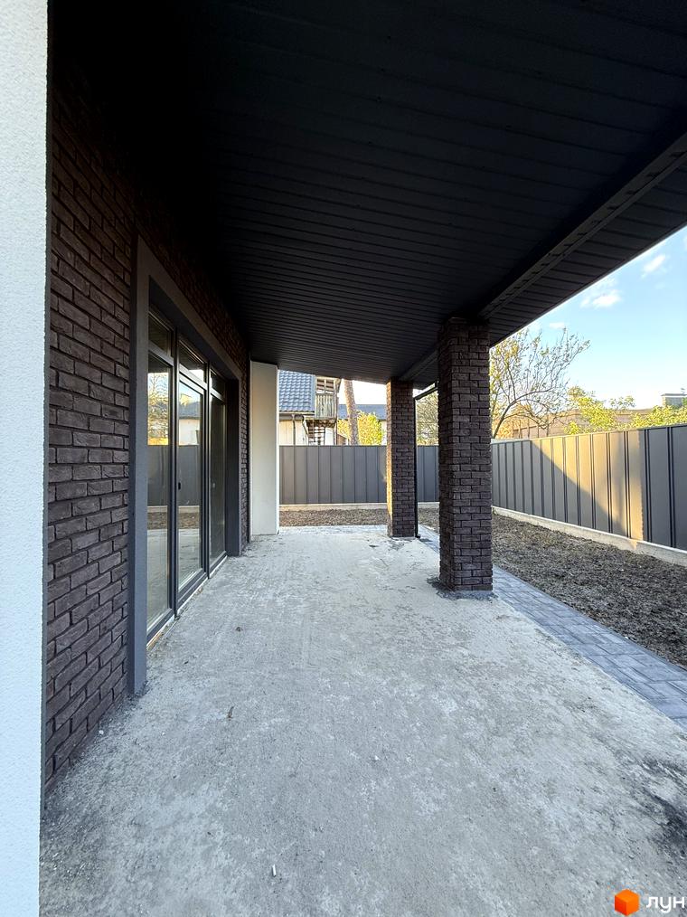 Зовнішній вигляд будинку КМ М-8А з цегляним фасадом та навісом, прибудинкова територія з бетонним покриттям та парканом.