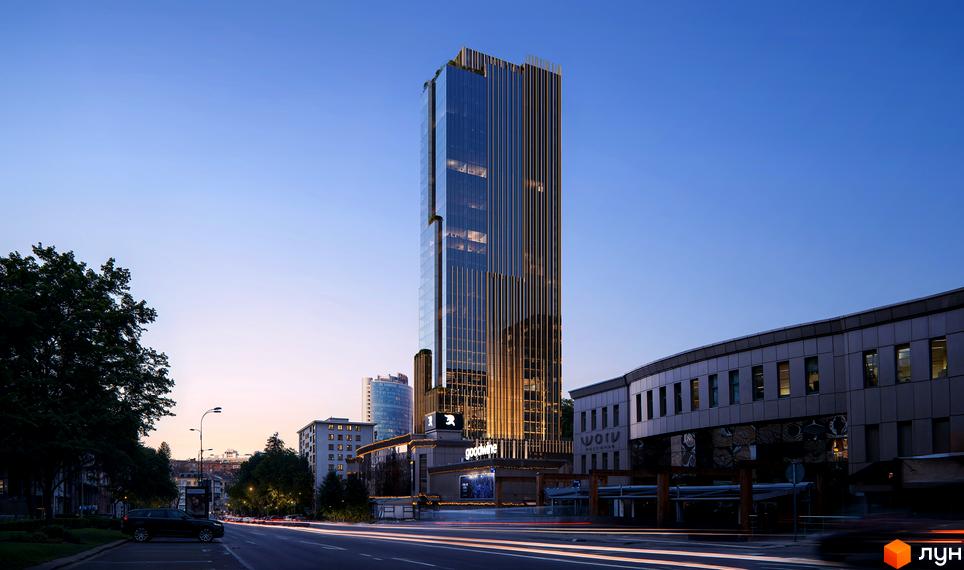 Зовнішній вигляд висотної новобудови THE ONE з скляним фасадом та вертикальними елементами на тлі вечірнього неба. Поруч розташована прибудинкова територія з деревами та дорогою.