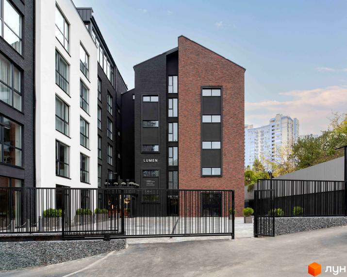 Житловий комплекс К11 з фасадами з білої та чорної цегли та червоної цегли. Навколо комплексу – огороджена територія з металевими воротами та парканом.