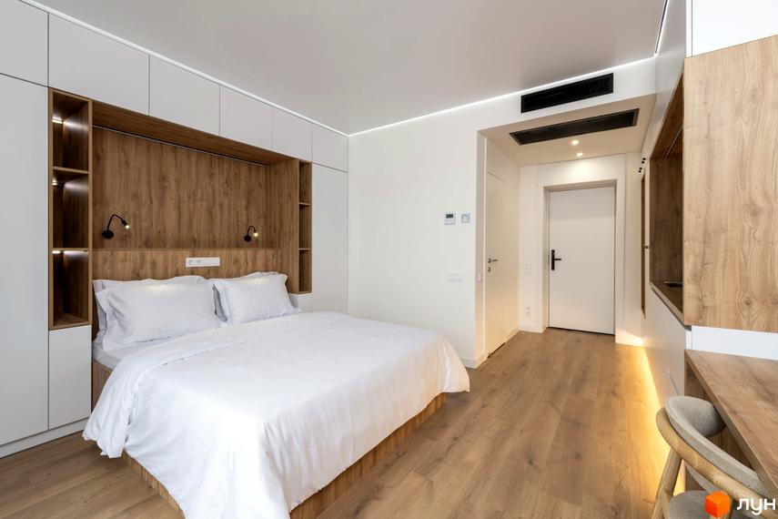 Інтер'єр спальні в Будівельному проєкті K11: велике ліжко з білою постіллю, дерев'яні панелі та шафи. Затишний та світлий дизайн кімнати.