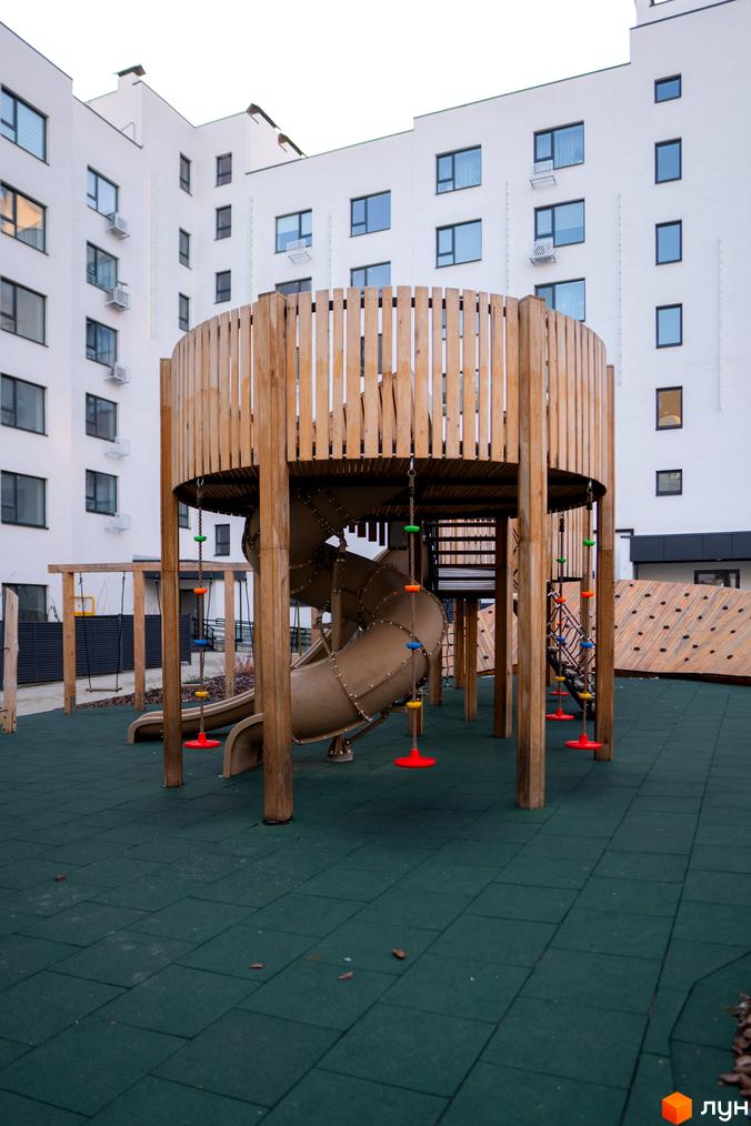 Сучасний дитячий майданчик біля білосніжної новобудови ЖК Синергія Light. Територія комплексу облаштована безпечним покриттям та ігровими елементами.