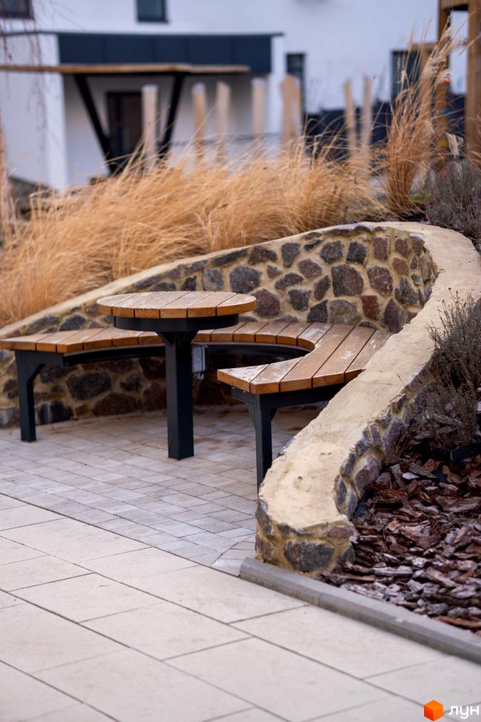 Зовнішній вигляд житлового комплексу Синергія Light з ландшафтним дизайном та зоною відпочинку. Прибудинкова територія з бруківкою та декоративними рослинами.