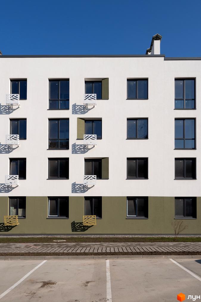 Фасад житлового комплексу Субурбія з великими вікнами та балконами. Поруч розташований паркінг та зелена зона.