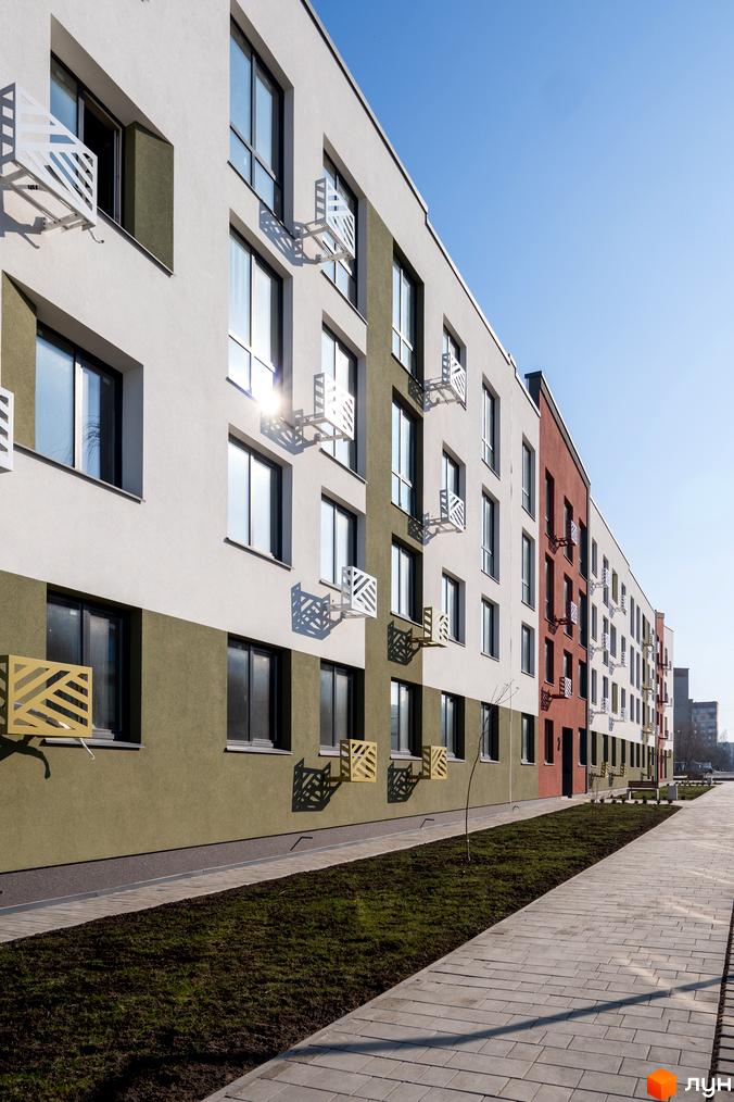 Зовнішній вигляд новобудови ЖК Субурбія з елементами декору на фасаді та доглянутою прибудинковою територією з тротуарною плиткою та зеленню.