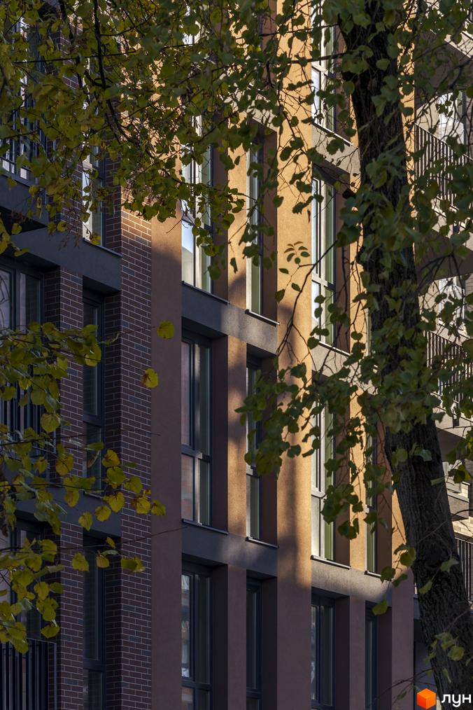 Житловий комплекс Avalon Yard з цегляним фасадом та великими вікнами, оточений деревами з осіннім листям.