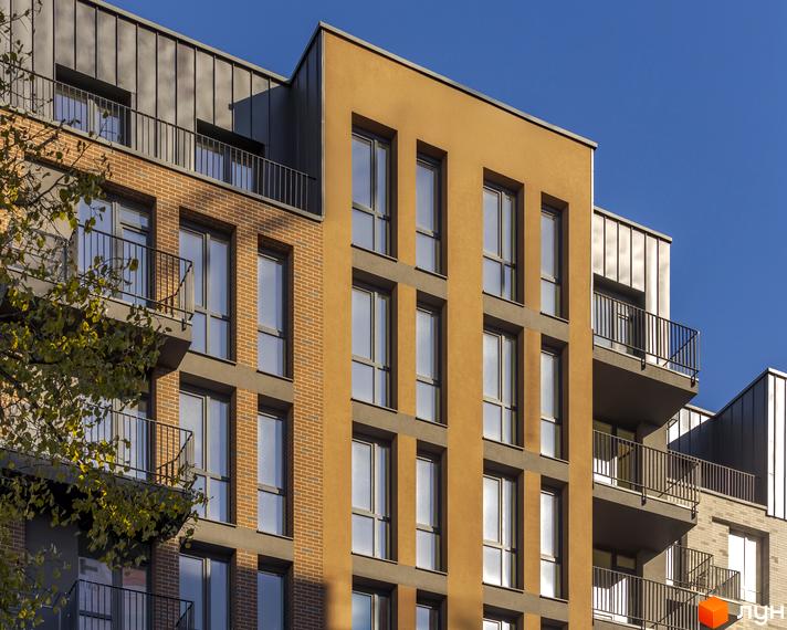 Житловий комплекс Avalon Yard з цегляним фасадом та балконами. Сучасна архітектура новобудови з великими вікнами та металевим дахом.