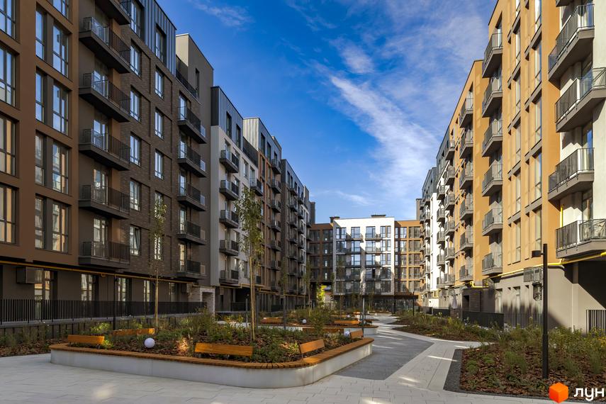 Житловий комплекс Avalon Yard з фасадами різних кольорів та балконами, упорядкована прибудинкова територія з лавками та зеленими насадженнями.