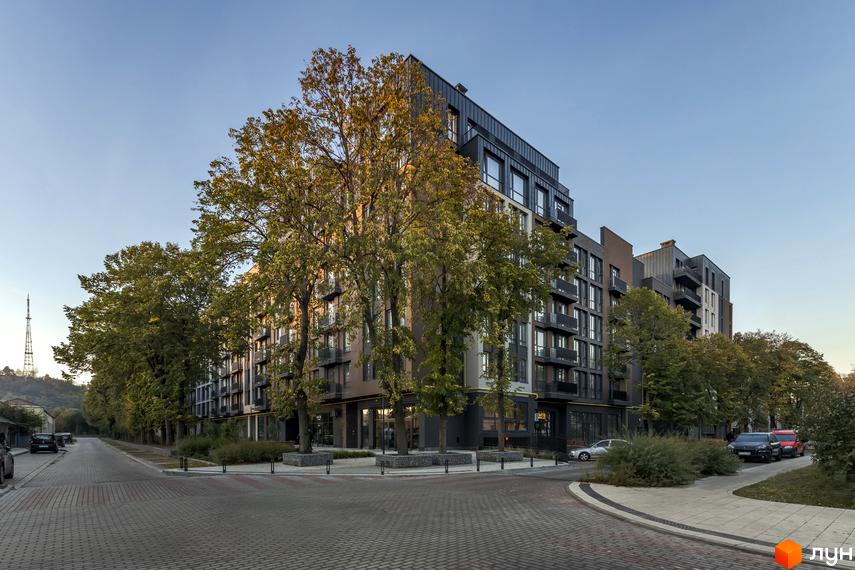 Житловий комплекс Avalon Yard з цегляним фасадом та балконами, оточений деревами. Територія комплексу з бруківкою та зеленими насадженнями.