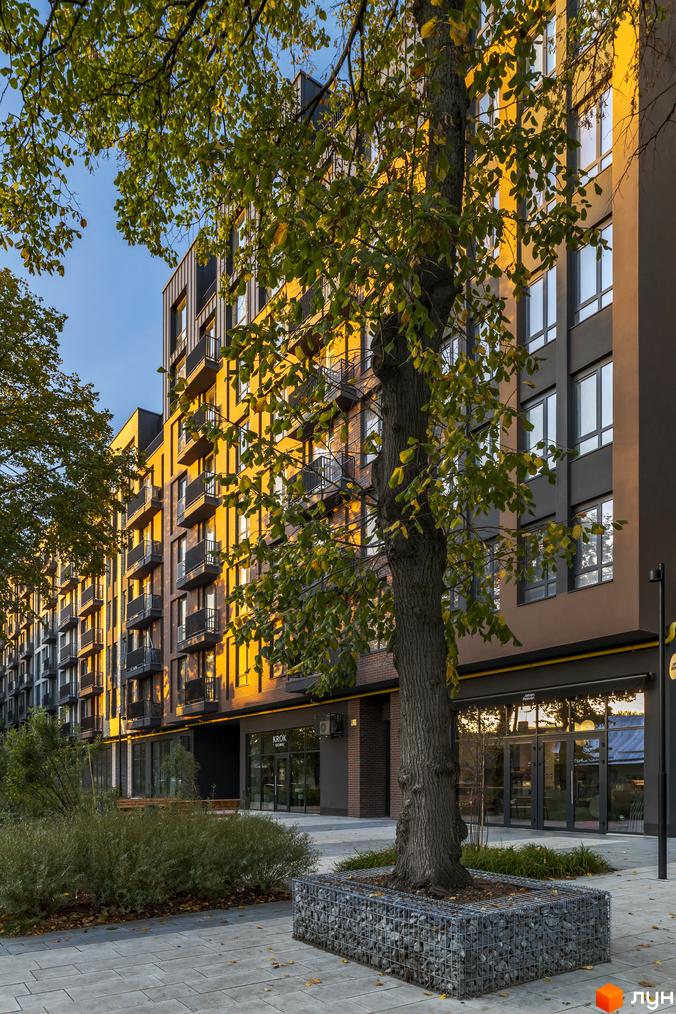 Житловий комплекс Avalon Yard з цегляним фасадом та балконами, оточений деревами та вимощеною прибудинковою територією.