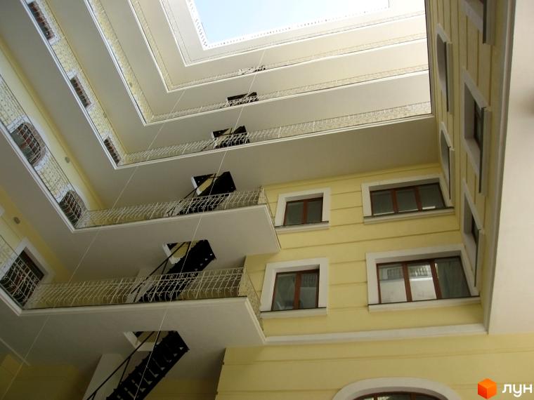 Житловий комплекс Ренесанс з балконами та відкритим внутрішнім двором. Вид на фасад та сходи з металевими перилами.