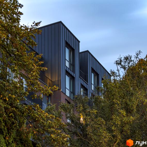 Житловий комплекс Avalon Yard з темним фасадом та цегляними елементами, оточений деревами з осіннім листям.
