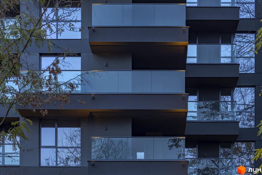 Фасад житлового комплексу Avalon Prime з балконами та великими вікнами, що відбивають дерева.