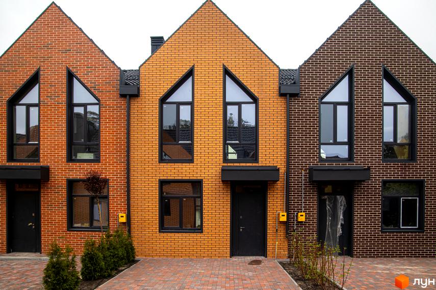 Зовнішній вигляд таунхаусів FORT HOMES з цегляним фасадом та великими вікнами. Перед будинками викладена бруківка.