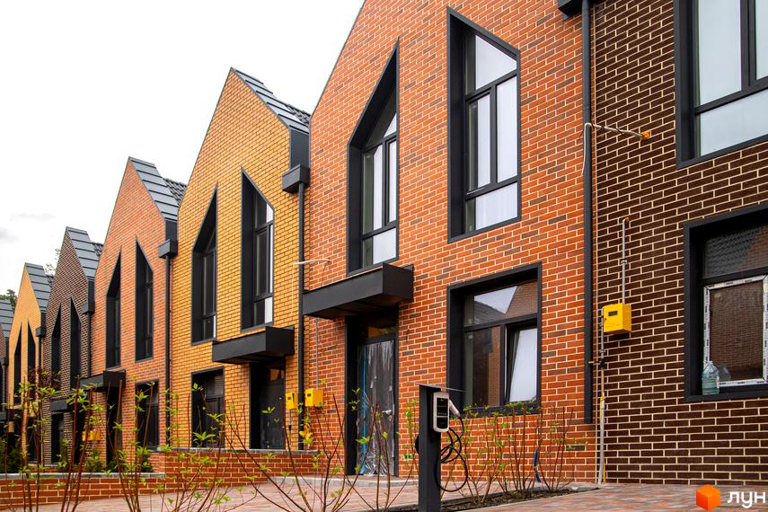 Зовнішній вигляд таунхаусів FORT HOMES з цегляними фасадами та великими вікнами. Упорядкована прибудинкова територія з рослинністю.