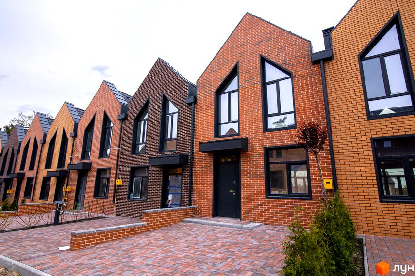 Зовнішній вигляд таунхаусів FORT HOMES з цегляним фасадом та великими вікнами. Прибудинкова територія вимощена бруківкою.