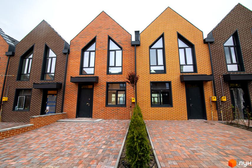 Таунхауси FORT HOMES з цегляним фасадом та панорамними вікнами, розташовані на брукованій прибудинковій території.