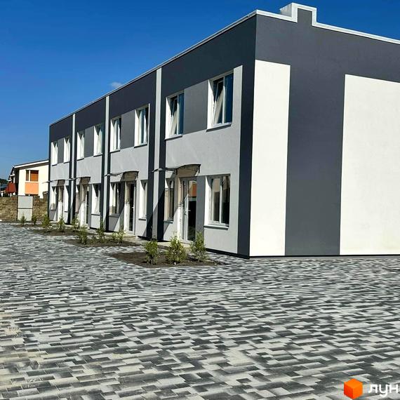 Зовнішній вигляд будинку в Котеджному містечку Family Park Residence. Фасад будівлі та вимощена плиткою прибудинкова територія.