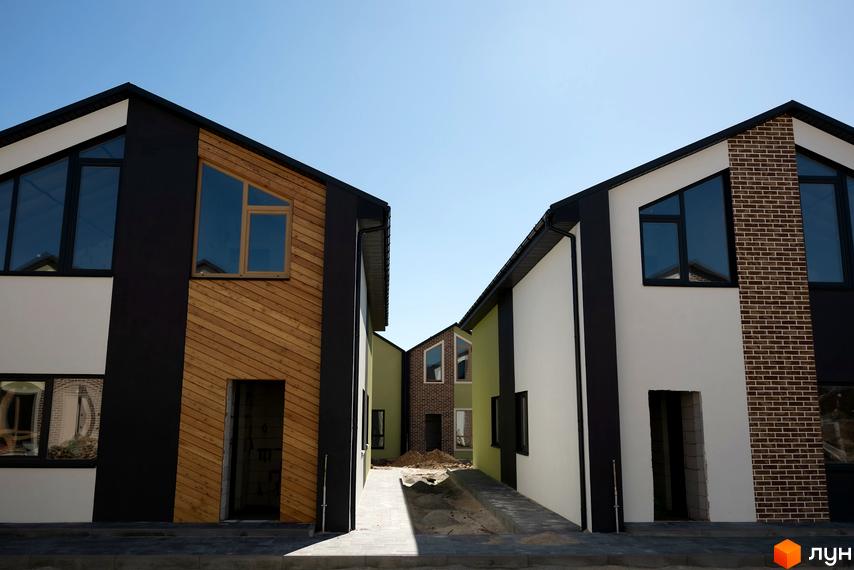 Зображення житлового комплексу Сітіхауси PRO MISTO. Будинки з панорамними вікнами та оздобленням фасаду деревом. Видно прибудинкову територію з бруківкою.