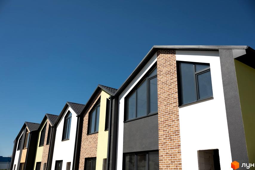 Фасади будинків житлового комплексу Сітіхауси PRO MISTO з цегляною кладкою, великими вікнами та блакитним небом.