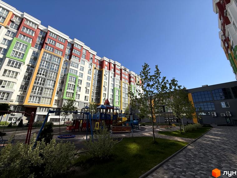 Зовнішній вигляд Житлового комплексу Добре Місто 2 з кольоровим фасадом. На території є дитячий майданчик та зелені насадження.