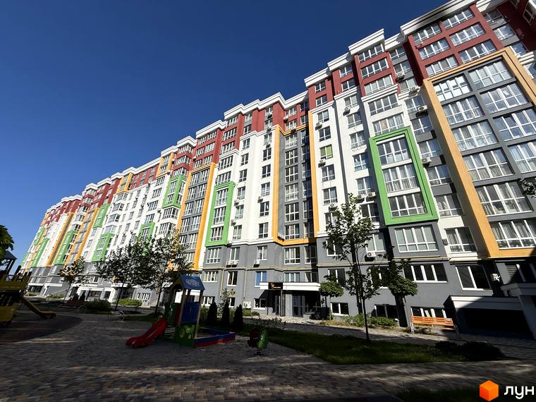 Багатоповерховий будинок ЖК Добре Місто 2 з яскравим фасадом та дитячим майданчиком на прибудинковій території.