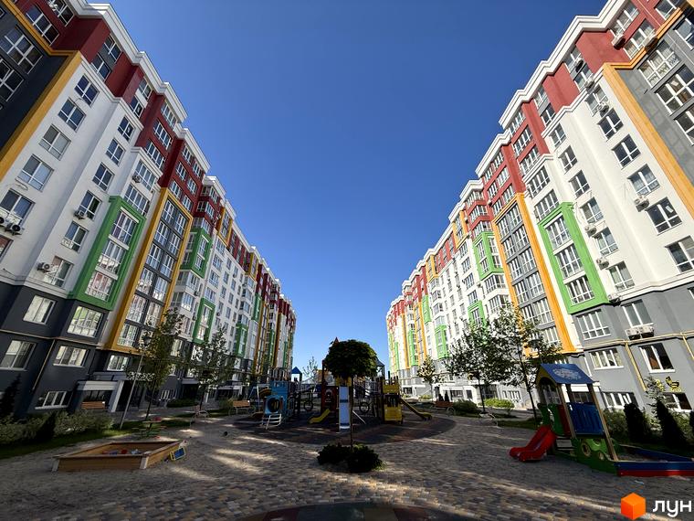 Високі будинки ЖК Добре Місто 2 з яскравими фасадами, дитячий майданчик та доглянута прибудинкова територія. Новобудова для комфортного життя.