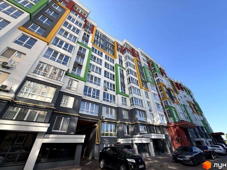 Зовнішній вигляд багатоповерхового будинку в Житловому районі Добре Місто 2. Навколо будівлі припарковані автомобілі.