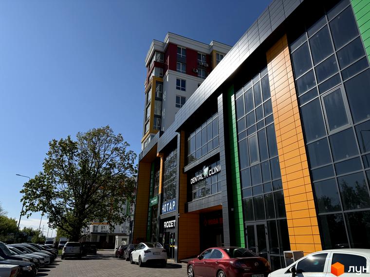 Зовнішній вигляд Будівельного проєкту Добре Місто 2. Багатоповерхова будівля з великими вікнами та яскравими кольоровими вставками на фасаді.