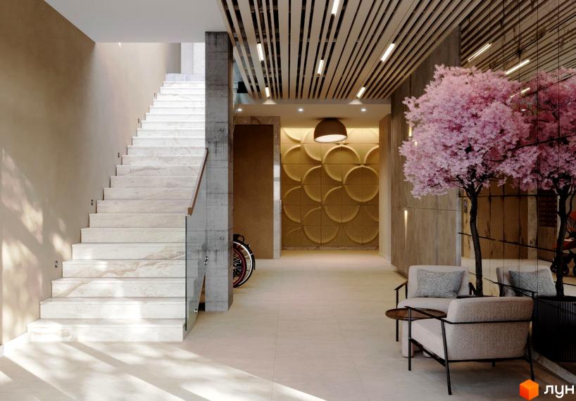 Просторий хол новобудови з мармуровими сходами та оригінальним оздобленням стін. Зона відпочинку з декоративними деревами створює атмосферу.