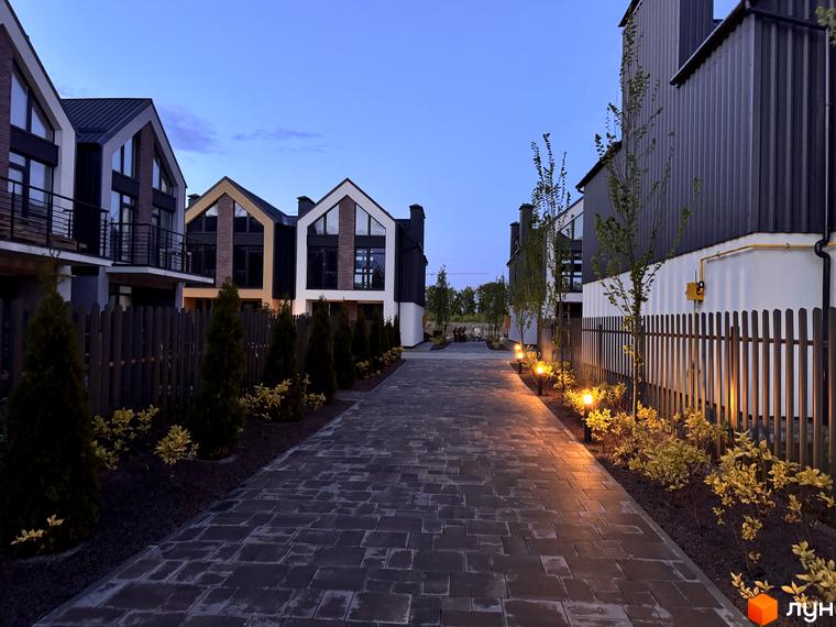 Таунхауси Петрівське містечко з цегляним фасадом та великими вікнами. Доглянута прибудинкова територія з доріжками та освітленням.