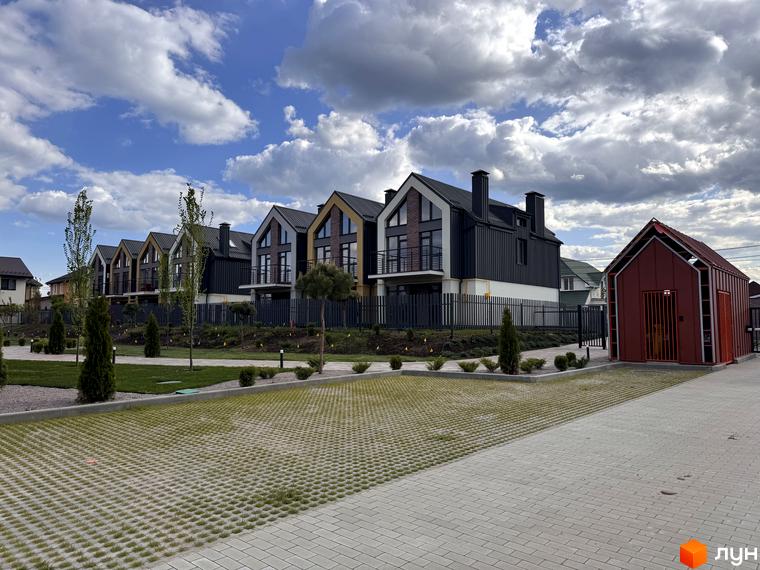 Котеджне містечко Петрівське містечко. Зовнішній вигляд таунхаусів з чорним фасадом та жовтими вставками, прибудинкова територія з паркуванням та зеленими насадженнями.