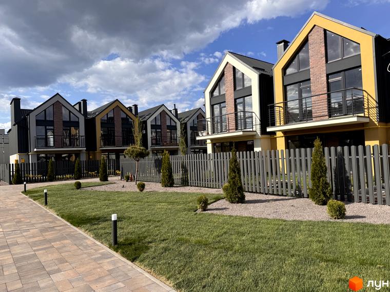 Таунхауси „Петрівське містечко“: фасади з панорамними вікнами та балконами, огороджена територія з газоном та декоративними деревами.